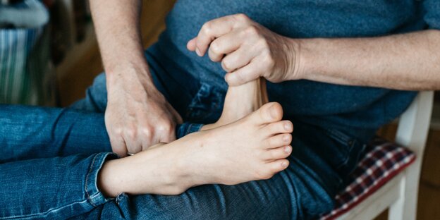 Kinderfüße, die ein Erwachsener hält Kinderfüße, die ein Erwachsener hält