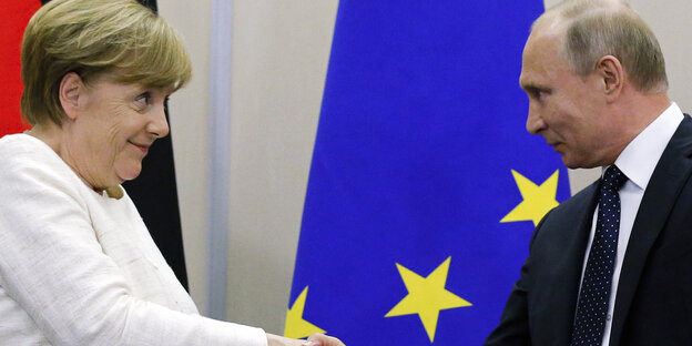 Merkel und Putin geben sich die Hand und schauen sich an Merkel und Putin geben sich die Hand und schauen sich an