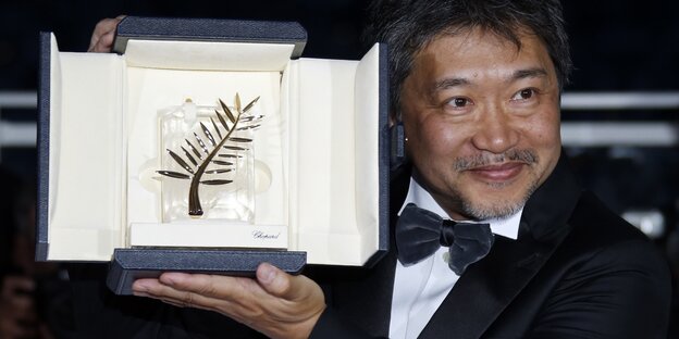 Ein Mann hält seine Goldene Palme in die Höhe Ein Mann hält seine Goldene Palme in die Höhe