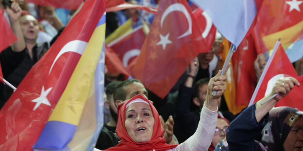 Eine Frau schwenkt Türkei-Flaggen in einer Menschenmenge Eine Frau schwenkt Türkei-Flaggen in einer Menschenmenge