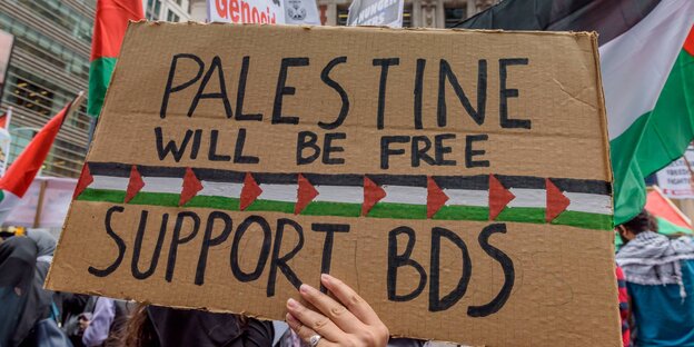 Eine Hand hält ein Schild auf dem Support BDS steht