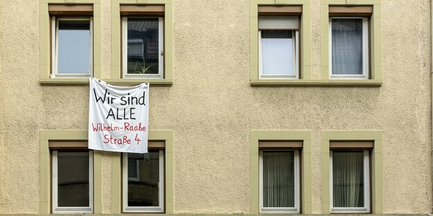 Ein Transparent hängt aus einem Fenster. Auf ihm steht: „Wir sind alle Wilhelm-Raabe-Straße 4“ Ein Transparent hängt aus einem Fenster. Auf ihm steht: „Wir sind alle Wilhelm-Raabe-Straße 4“