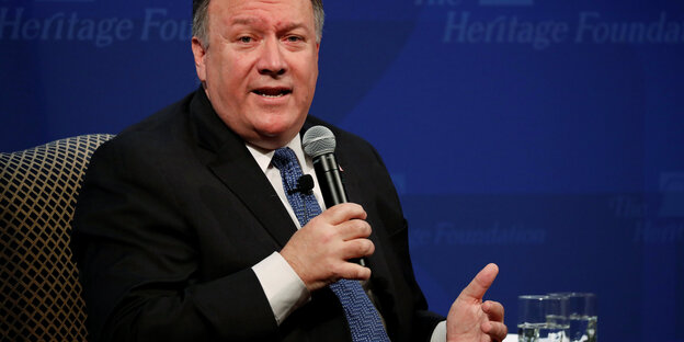 Mike Pompeo sitzt auf einem Sessel und hält ein Mikrofon in der Hand Mike Pompeo sitzt auf einem Sessel und hält ein Mikrofon in der Hand