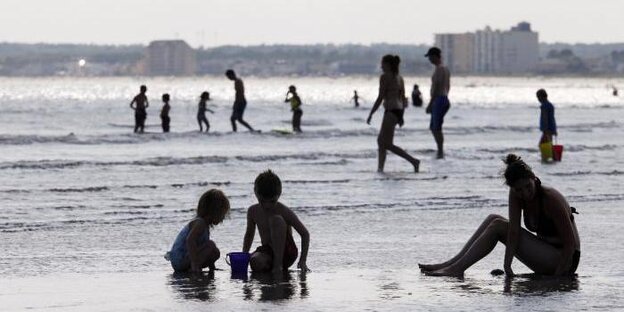 zwei Kinder und eine Frau sitzen am Strand zwei Kinder und eine Frau sitzen am Strand