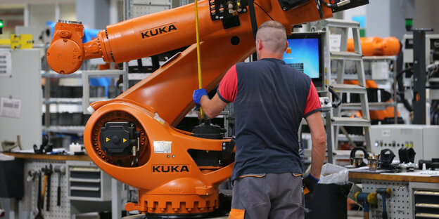 Ein Arbeiter steht vor einem Roboter Ein Arbeiter steht vor einem Roboter