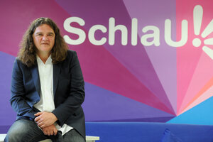 Ein Mann sitzt vor einer bunten Wand mit der Aufschrift „Schlau!“ Ein Mann sitzt vor einer bunten Wand mit der Aufschrift „Schlau!“