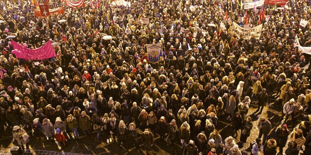 Viele Männer und Frauen stehen in Mänteln auf einem Platz in Oslo