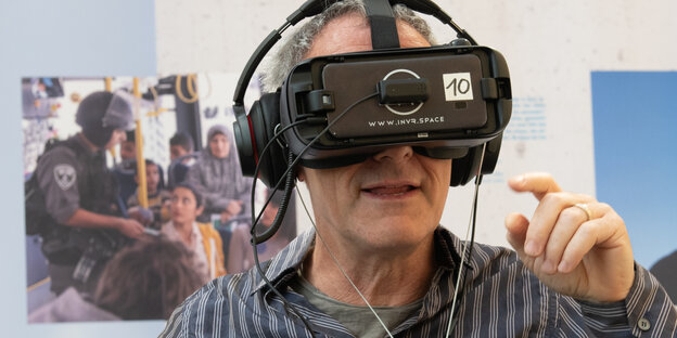 Der Regisseur Dani Levy hat eine schwarze Virtual Reality Brille und Kopfhörer auf Der Regisseur Dani Levy hat eine schwarze Virtual Reality Brille und Kopfhörer auf