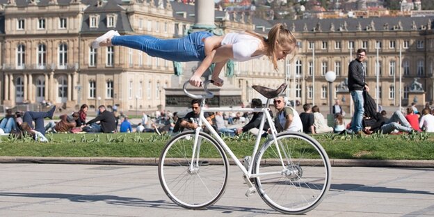 Eine Frau macht eine Kunstfigur auf einem Fahrrad Eine Frau macht eine Kunstfigur auf einem Fahrrad