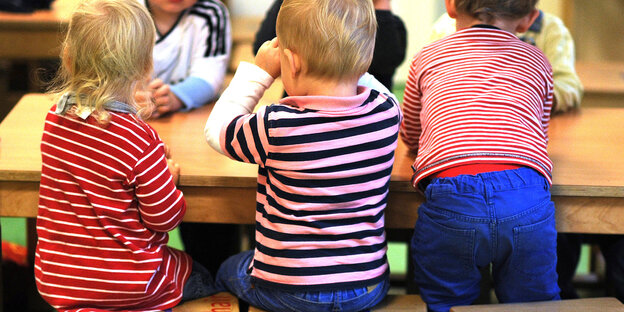 Drei Kinder sitzen an einem Tisch Drei Kinder sitzen an einem Tisch