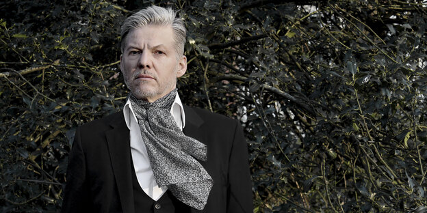 Ein schick angezogener Mann, Wolfgang Voigt, steht vor einer Hecke Ein schick angezogener Mann, Wolfgang Voigt, steht vor einer Hecke