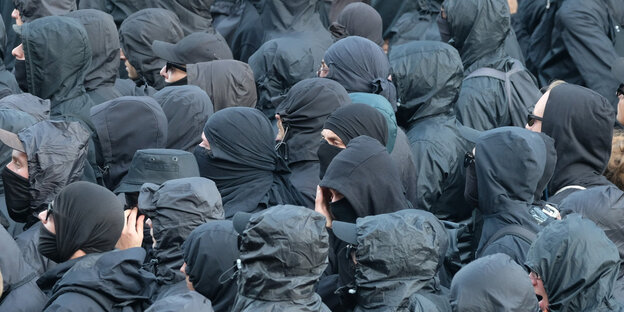eine Menge Menschen in schwarzer Kleidung, die Gesichter durch Kapuzen und Schals oder Tücher verhüllt eine Menge Menschen in schwarzer Kleidung, die Gesichter durch Kapuzen und Schals oder Tücher verhüllt