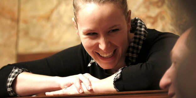 Marion Maréchal-Le Pen hat fast den Kopf auf ihre Arme gestützt und lacht in Richtung eines Mannes Marion Maréchal-Le Pen hat fast den Kopf auf ihre Arme gestützt und lacht in Richtung eines Mannes
