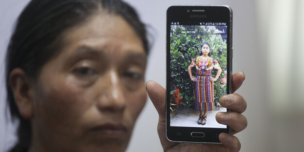 Eine Frau hält ein Smartphone mit einem Bild einer jungen Frau hoch. Eine Frau hält ein Smartphone mit einem Bild einer jungen Frau hoch.