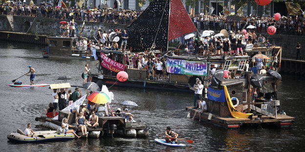 Schiffsgewimmel mit vielen Menschen und Transparenten auf der Spree