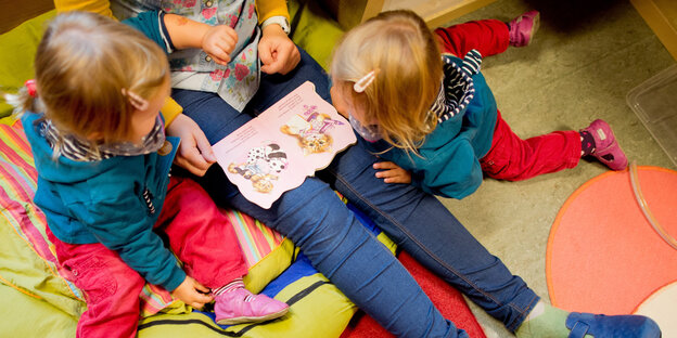 Zwei Kinder sitzen neben einer erwachsenen Person Zwei Kinder sitzen neben einer erwachsenen Person