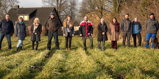 Elf Leute stehen nebeneinander auf einem Feld