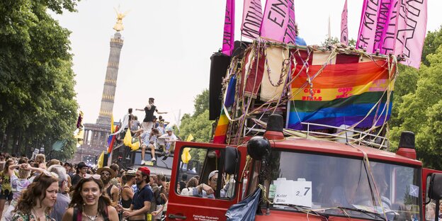 Viele Menschen, ein großes Auto mit Regenbogen- und pinken Fahnen, im Hintergrund die Siegessäule Viele Menschen, ein großes Auto mit Regenbogen- und pinken Fahnen, im Hintergrund die Siegessäule