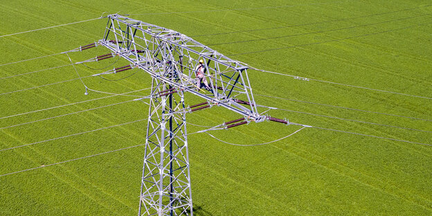 Strommast auf grünem Acker Strommast auf grünem Acker