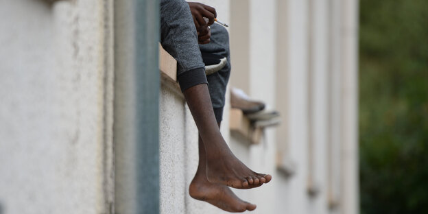 Ein Asylbewerber sitzt auf dem Fensterbrett einer Asylunterkunft Ein Asylbewerber sitzt auf dem Fensterbrett einer Asylunterkunft