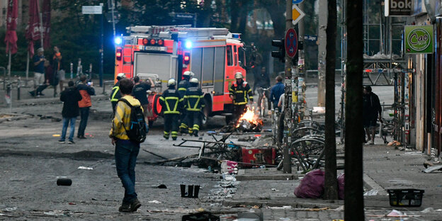 Ein Feuerwehrauto und Feuerwehrleute stehen auf einer Straße, die voller Müll ist Ein Feuerwehrauto und Feuerwehrleute stehen auf einer Straße, die voller Müll ist