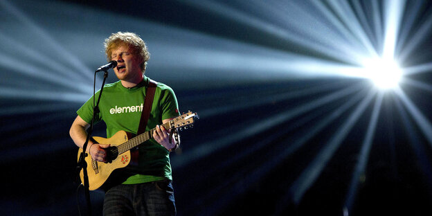 Ed Sheeran steht mit Gitarre auf der Bühne und singt Ed Sheeran steht mit Gitarre auf der Bühne und singt