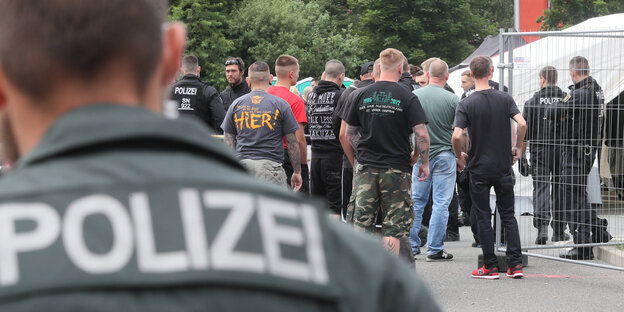 Ein Polizist beobachtet eine Gruppe Neonazis Ein Polizist beobachtet eine Gruppe Neonazis