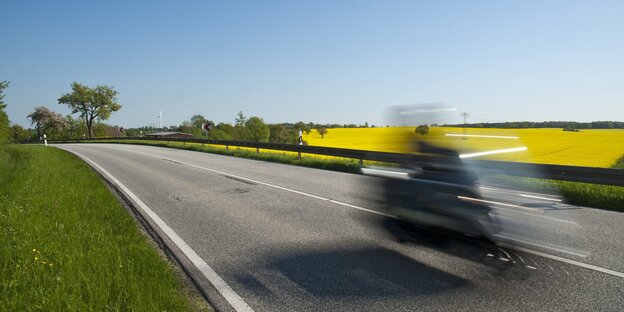 ein Motorrad braust über eine Landstraße - es ist verwischt zu sehen, da mit längerer Belichtungszeit aufgenommen ein Motorrad braust über eine Landstraße - es ist verwischt zu sehen, da mit längerer Belichtungszeit aufgenommen
