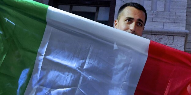 Luigi di Maio schaut hinter einer Italienflagge hervor Luigi di Maio schaut hinter einer Italienflagge hervor