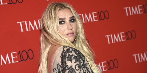 Sängerin Kesha steht vor einer roten Wand Sängerin Kesha steht vor einer roten Wand