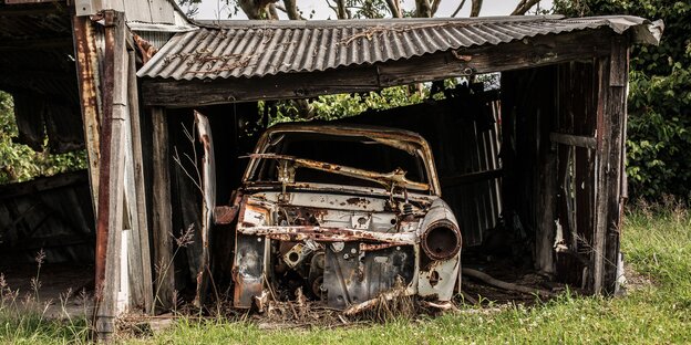 Ein rostendes Auto in einer rostenden Garage Ein rostendes Auto in einer rostenden Garage