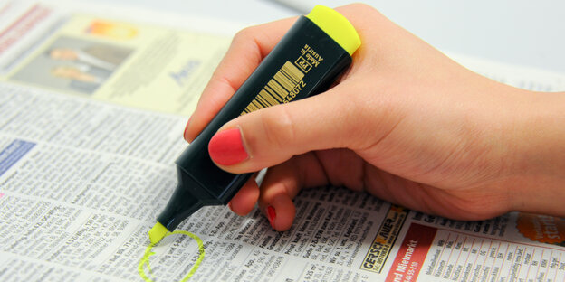 Eine Hand markiert mit Textmarker Wohnungsangebote einer Zeitung Eine Hand markiert mit Textmarker Wohnungsangebote einer Zeitung