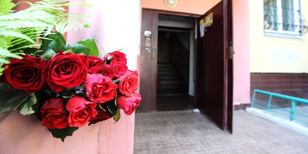 Ein Bund Rosen an einem Pfeiler am Eingang eines Hauses. Die Haustür steht offen Ein Bund Rosen an einem Pfeiler am Eingang eines Hauses. Die Haustür steht offen