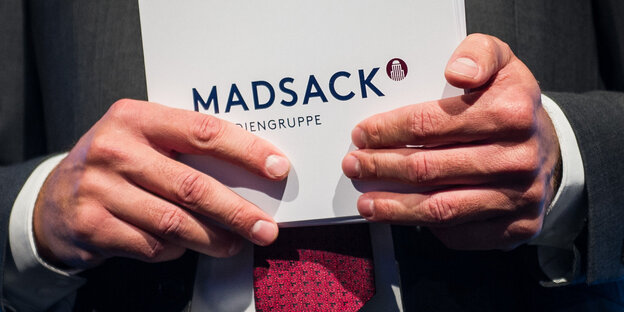 Ein Mann Moderationskarten mit der Aufschrift "Madsack" in den Händen Ein Mann Moderationskarten mit der Aufschrift "Madsack" in den Händen