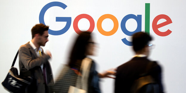 In bunten Buchstaben steht auf einer weißen Wand das Wort „Google“, davor gehen Menschen vorbei In bunten Buchstaben steht auf einer weißen Wand das Wort „Google“, davor gehen Menschen vorbei