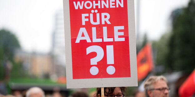 Ein Frau hält ein Schild mit der Aufschrift "Wohnen für Alle?!" hoch. Ein Frau hält ein Schild mit der Aufschrift "Wohnen für Alle?!" hoch.