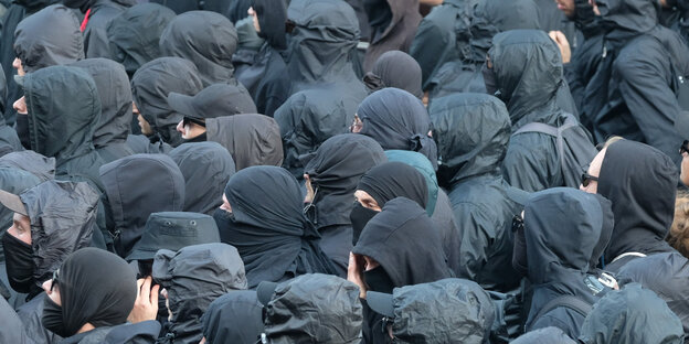 Viele vermummte Menschen in schwarzer Kleidung und Sonnebrillen Viele vermummte Menschen in schwarzer Kleidung und Sonnebrillen