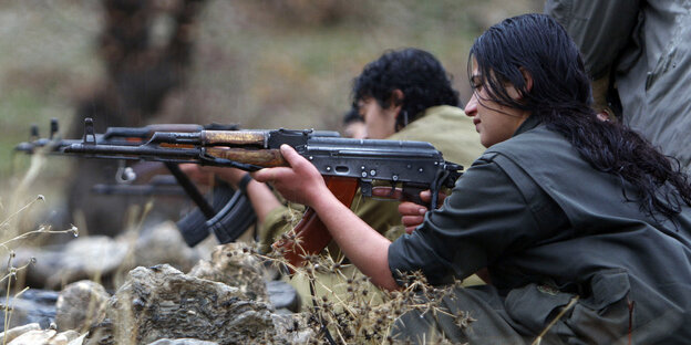 Eine kurdische Frau der PKK zielt mit einem Gewehr. Eine kurdische Frau der PKK zielt mit einem Gewehr.