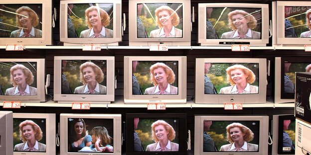 Über ein Dutzend Fernseher stehen in drei Reihen hintereinander, auf den meisten von ihnen ist eine blonde Frau zu sehen Über ein Dutzend Fernseher stehen in drei Reihen hintereinander, auf den meisten von ihnen ist eine blonde Frau zu sehen