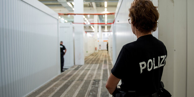 Eine Polizistin steht in einem langen Gang Eine Polizistin steht in einem langen Gang