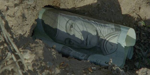 Ein Mitschnitt aus dem Dokumentarfilm „El mar la mar“ zeigt einen Geldschein im Sand Ein Mitschnitt aus dem Dokumentarfilm „El mar la mar“ zeigt einen Geldschein im Sand