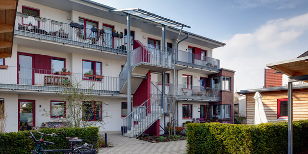 Ein mehrgeschossiges neues Wohnhaus, davor Hecken Ein mehrgeschossiges neues Wohnhaus, davor Hecken