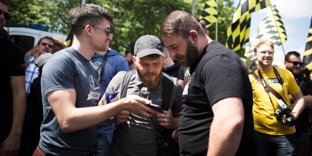 Martin Sellner und zwei andere Männer gucken bei einer Demonstration auf ein Smartphone Martin Sellner und zwei andere Männer gucken bei einer Demonstration auf ein Smartphone
