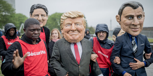 Menschen mit großen Gesichtsmasken gehen neben Menschen mit roten Westen Menschen mit großen Gesichtsmasken gehen neben Menschen mit roten Westen