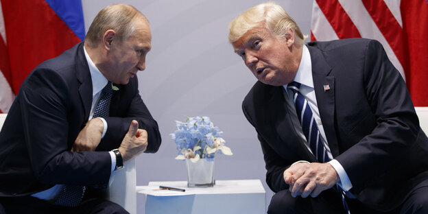 Wladimir Putin und Donald Trump sitzen nebeneinander und reden miteinander Wladimir Putin und Donald Trump sitzen nebeneinander und reden miteinander