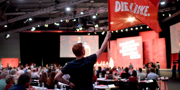Ein Teilnehmer des Parteitags der Linken schwenkt eine Fahne. Ein Teilnehmer des Parteitags der Linken schwenkt eine Fahne.