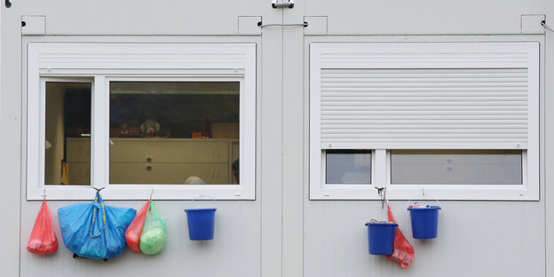 Tüten und Eimer hängen aus den Fenstern eines Wohncontainers. Tüten und Eimer hängen aus den Fenstern eines Wohncontainers.