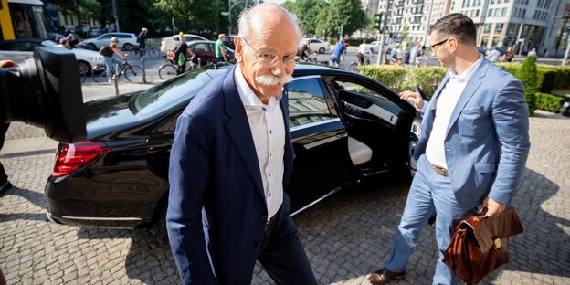 Dieter Zetsche schaut in die Kamera. Im Hintergrund ist ein Mercedes zu sehen