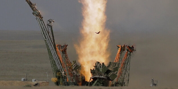 Feuerstrahl eines Raketenstarts, Teile eines Stützgerüsts fallen zur Seite Feuerstrahl eines Raketenstarts, Teile eines Stützgerüsts fallen zur Seite
