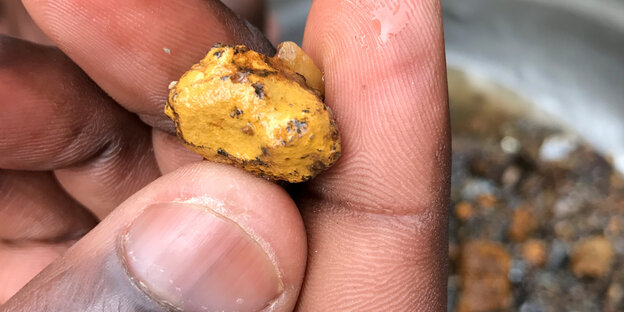 ein winziges Klümpchen Gold zwischen Daumen und Zeigefinger ein winziges Klümpchen Gold zwischen Daumen und Zeigefinger